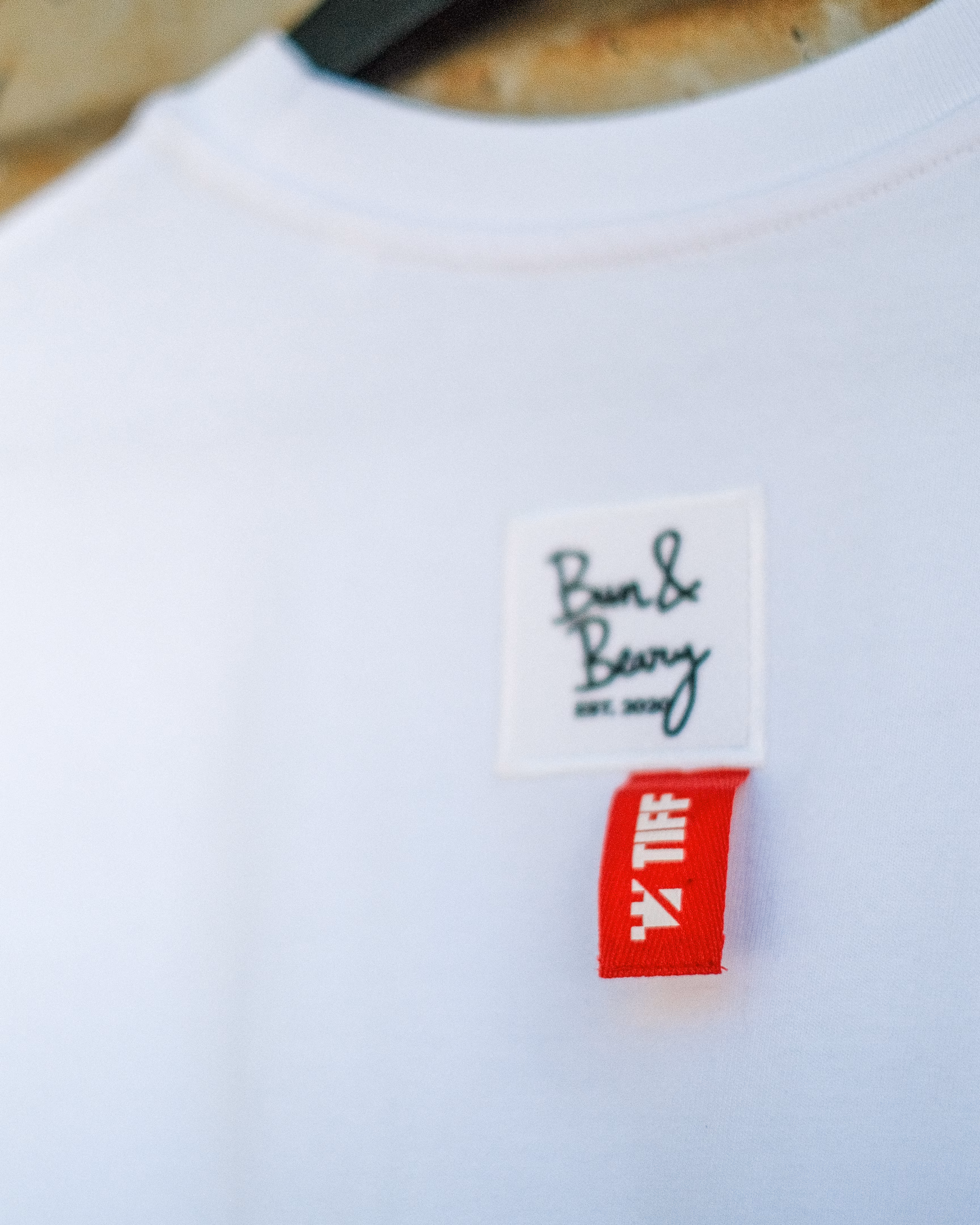 Close-up of the Bun&Beary and red TIFF labels stitched onto the back of the white T-shirt